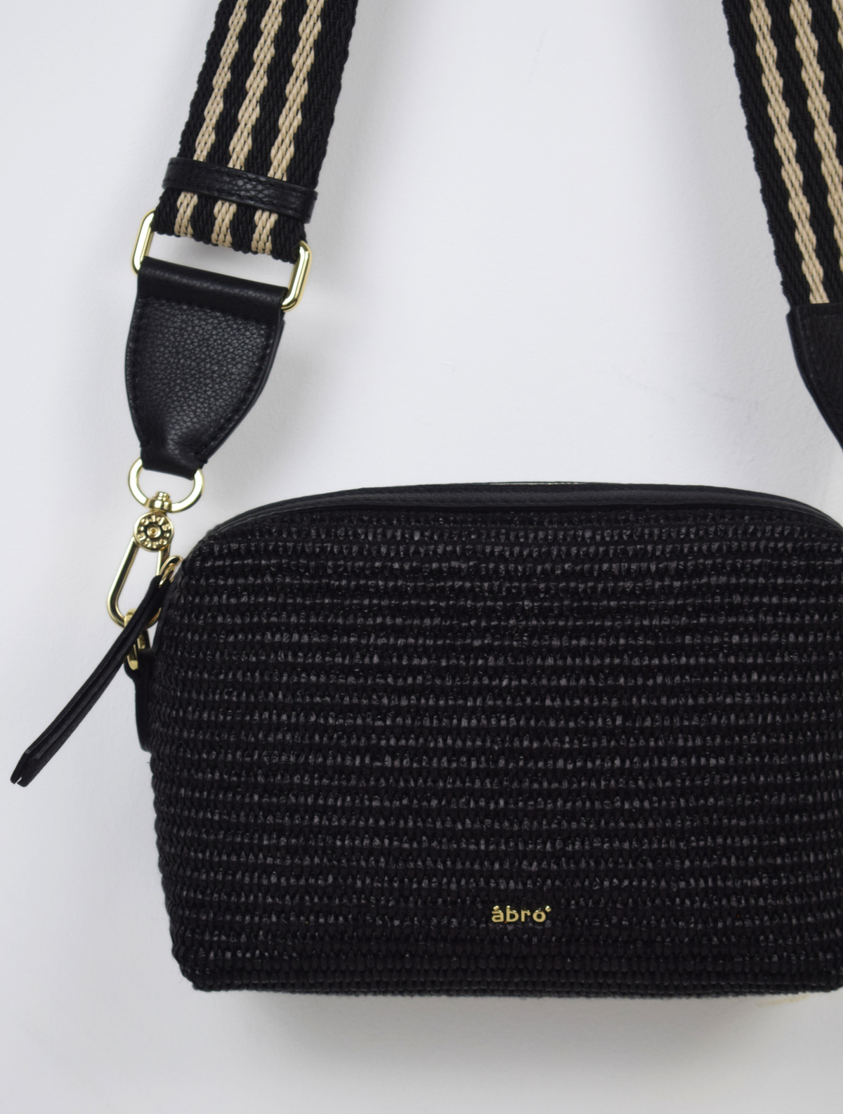 A black raffia bag with a stripe strap. 