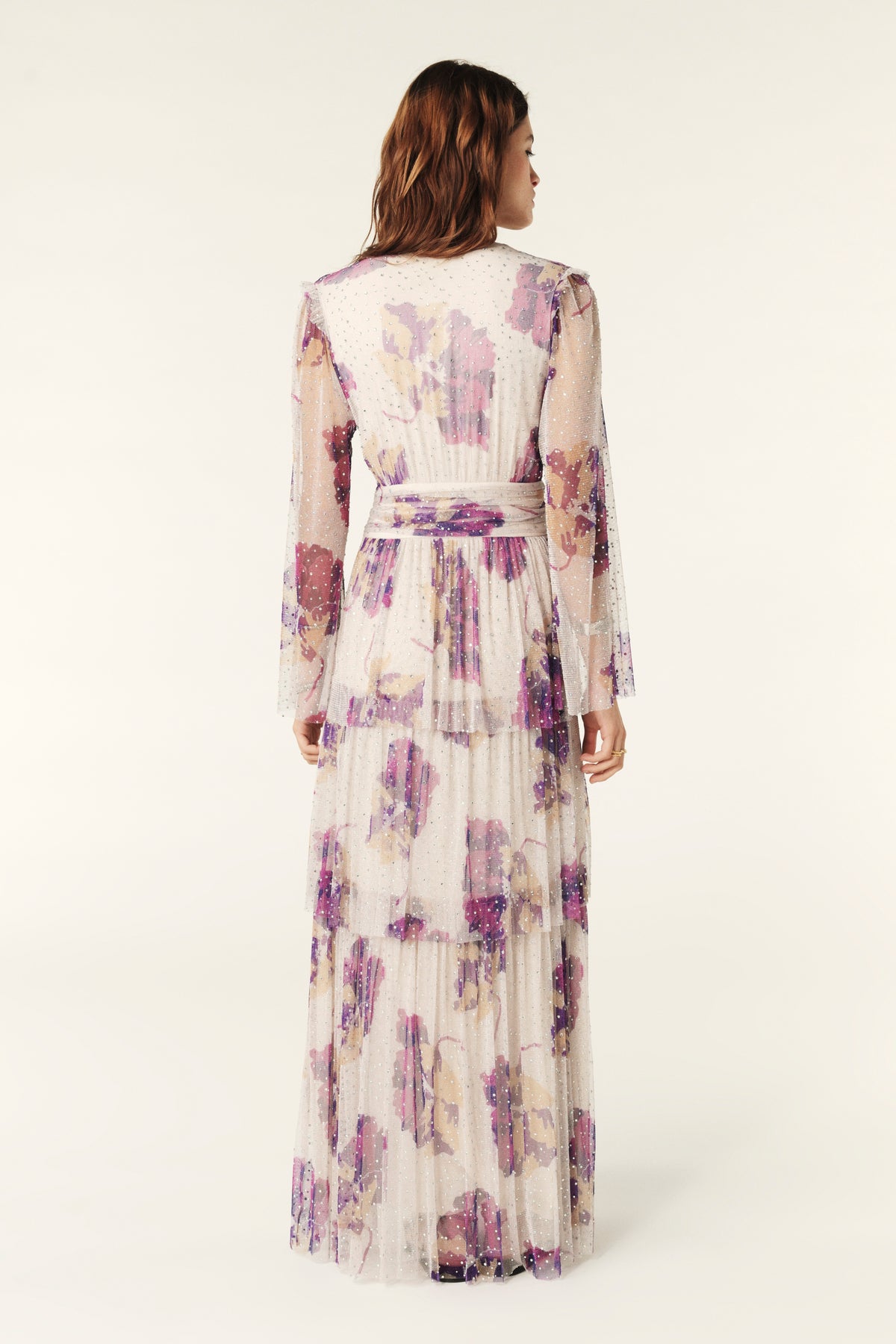 Ecru V neck maxi dress with fluted sheer sleeves empire line and purple floral design with net overlay with iridescent gems all over