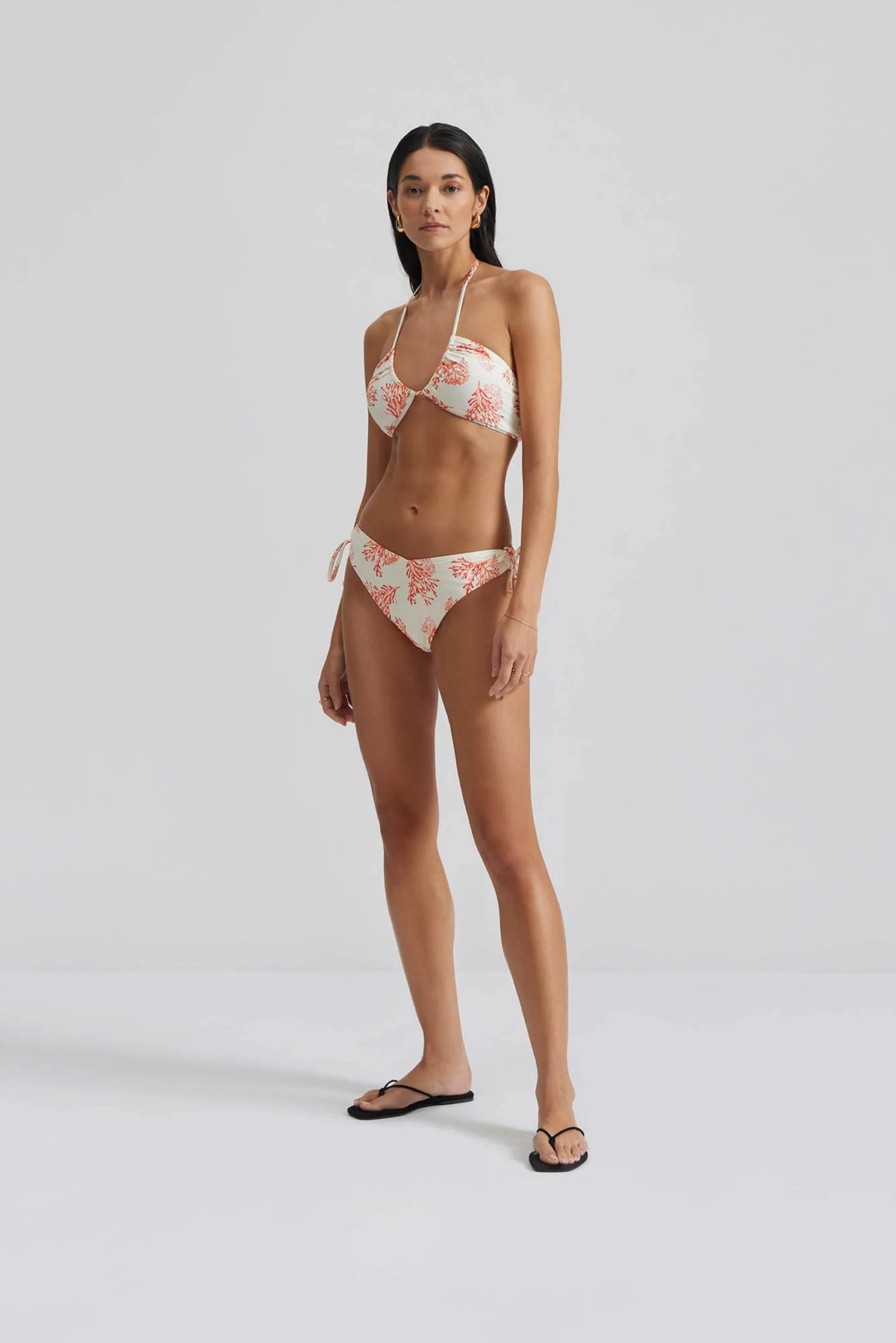 Ecru low rise bikini bottoms with side ruched ties and red/orange coral print