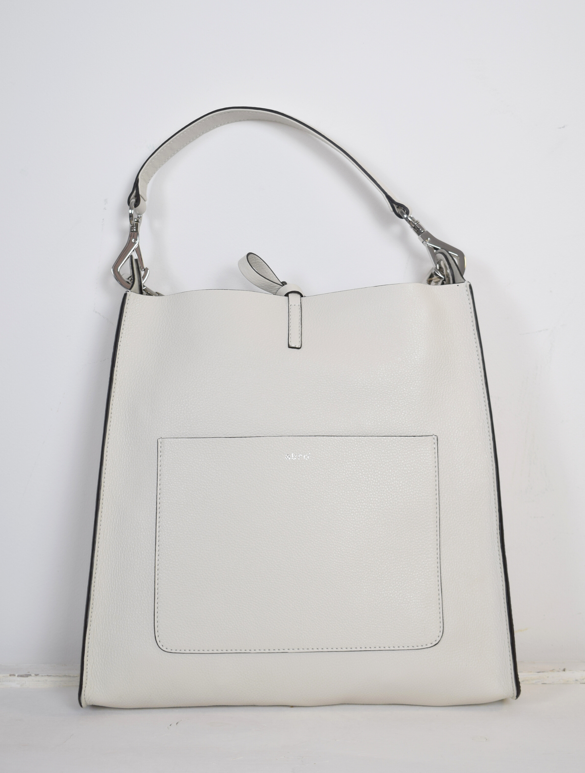 ivory leather bag with silver hardware.  A cross body strap and a handle. 