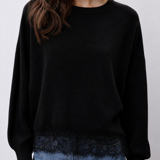 model wearing a black crew neckline knit with lace hem and blue jeans 