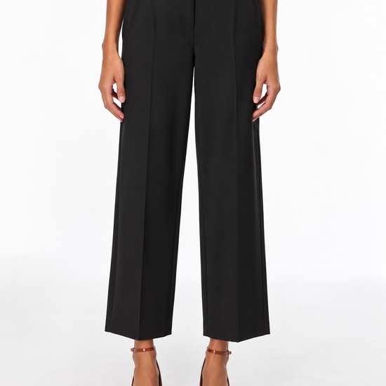 A model is shown from the waist down wearing black wide-leg cropped trousers, paired with a cream top and brown patent leather heels, against a plain white studio background.