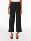 A model is shown from the waist down wearing black wide-leg cropped trousers, paired with a cream top and brown patent leather heels, against a plain white studio background.