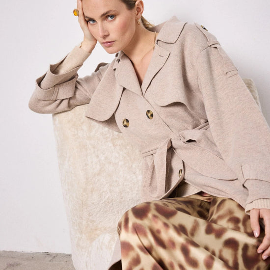 Model shot of beige knitted trench coat worn with skirt