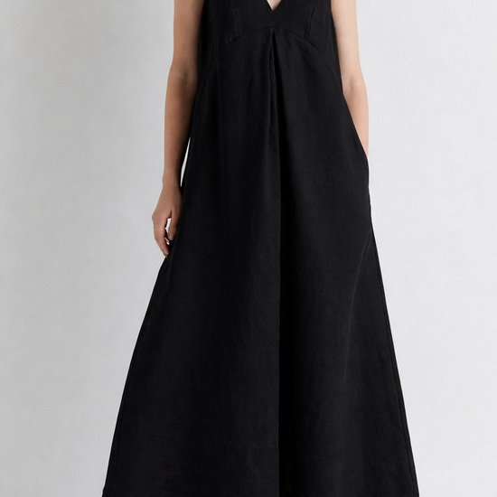 Woman wearing a black sleeveless dress on a plain background