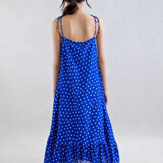 Woman wearing a blue polka dot dress on a plain background