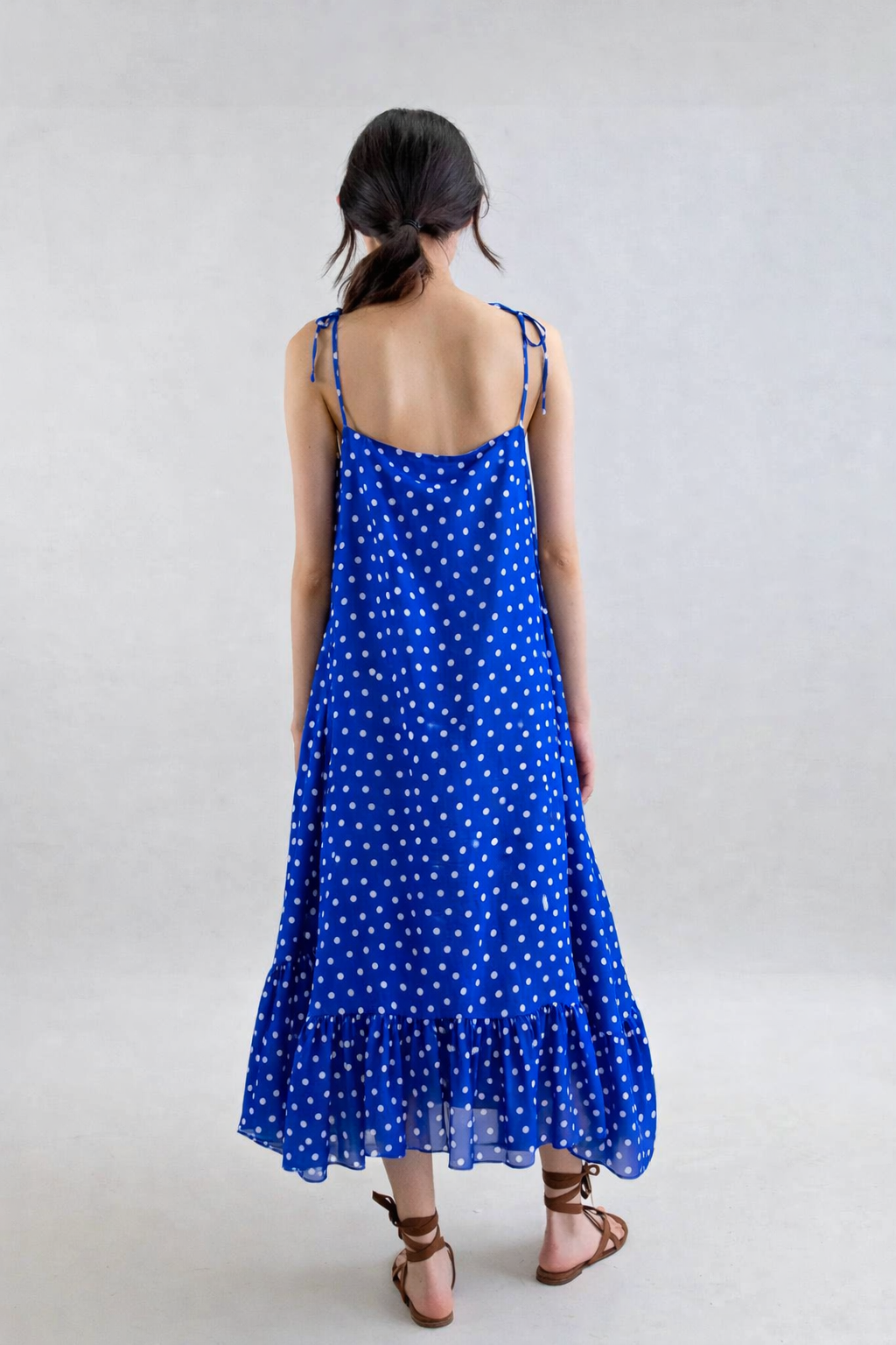 Woman wearing a blue polka dot dress on a plain background