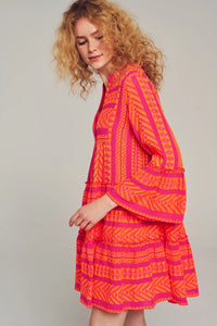 Fuscia pink notch neck above the knee dress with long fluted sleeves and tripe tiered A line skirt with neon orange embroidery throughout