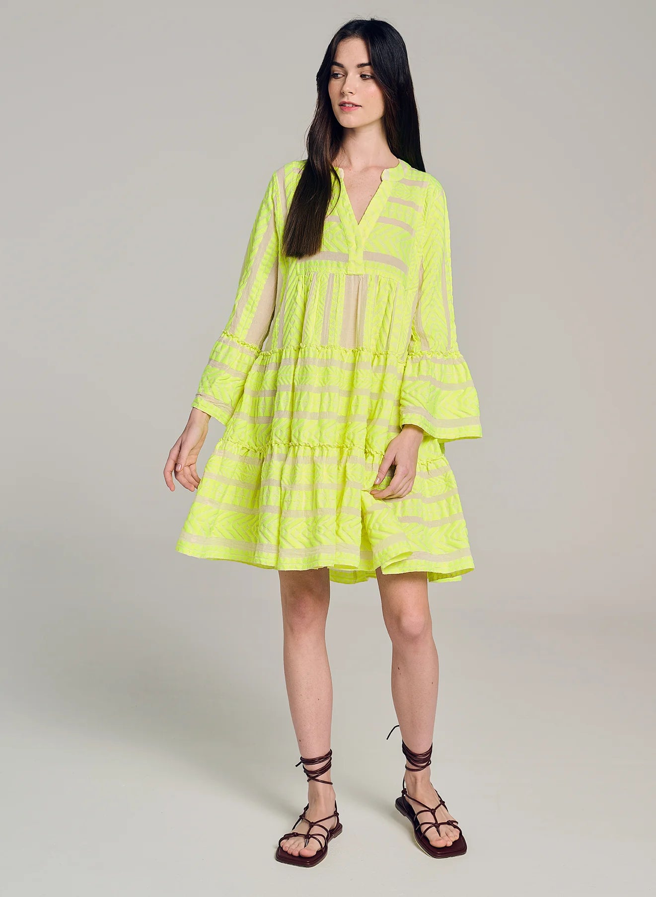 Ecru notch neck above the knee dress with long fluted sleeves and tripe tiered A line skirt with neon lime embroidery throughout