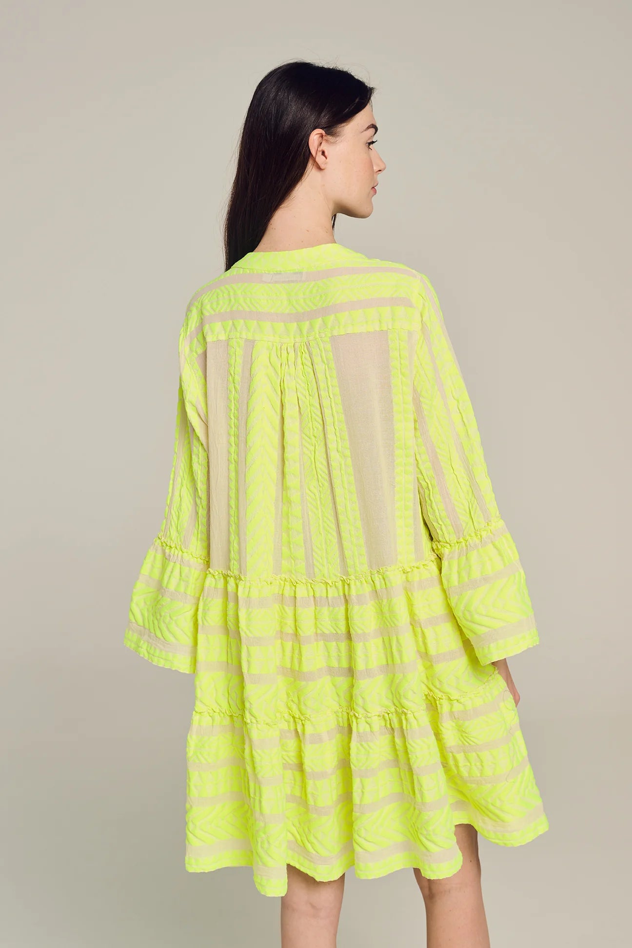 Ecru notch neck above the knee dress with long fluted sleeves and tripe tiered A line skirt with neon lime embroidery throughout