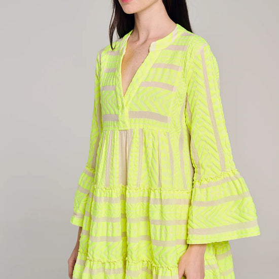 Ecru notch neck above the knee dress with long fluted sleeves and tripe tiered A line skirt with neon lime embroidery throughout