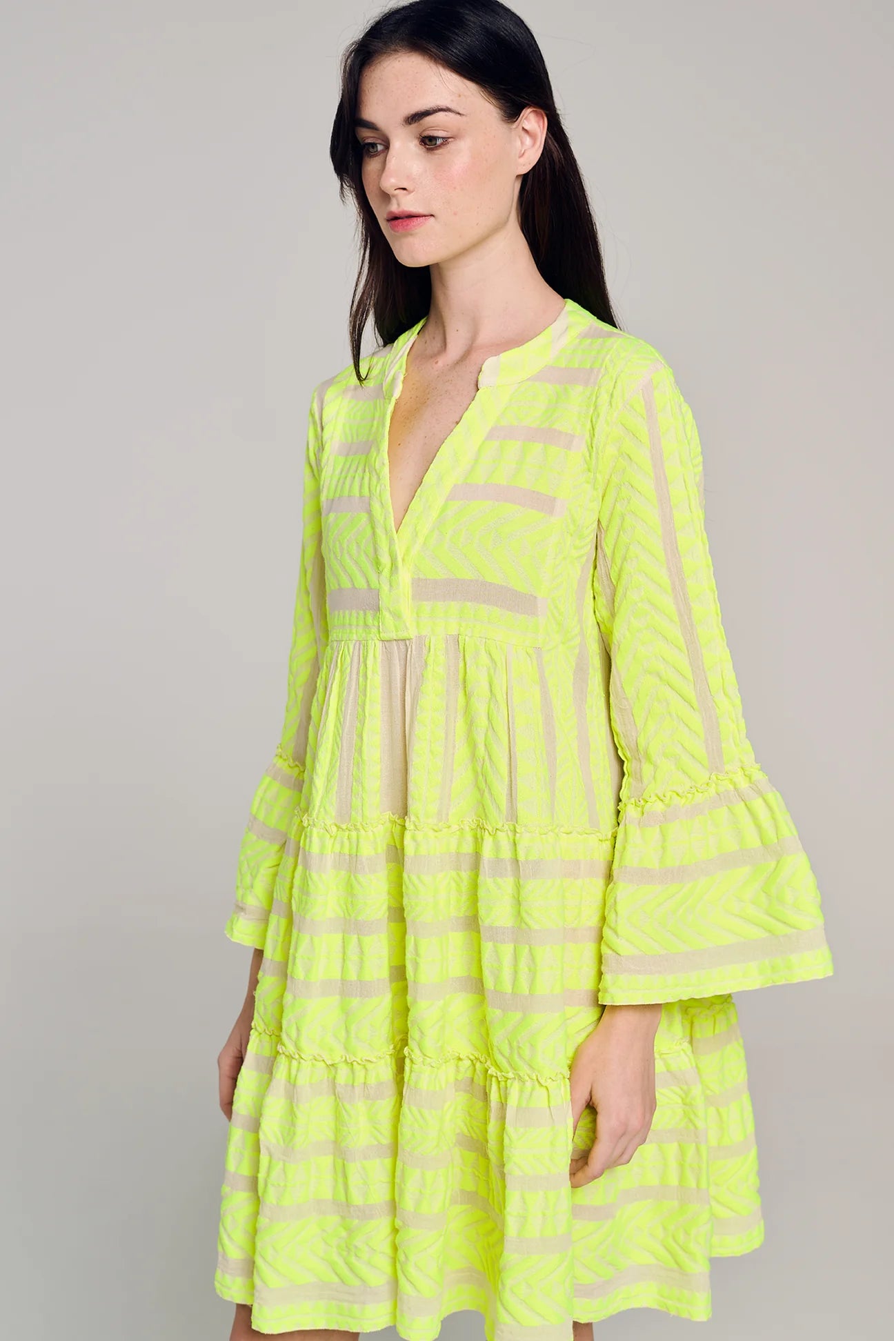 Ecru notch neck above the knee dress with long fluted sleeves and tripe tiered A line skirt with neon lime embroidery throughout