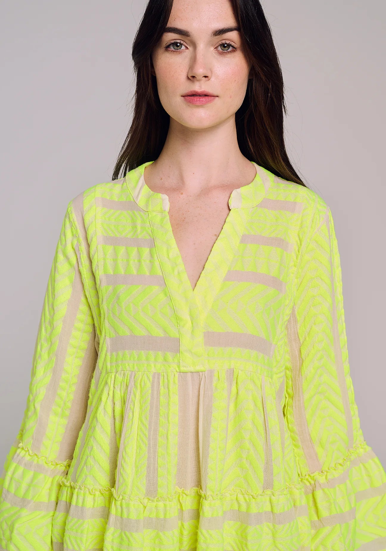 Ecru notch neck above the knee dress with long fluted sleeves and tripe tiered A line skirt with neon lime embroidery throughout