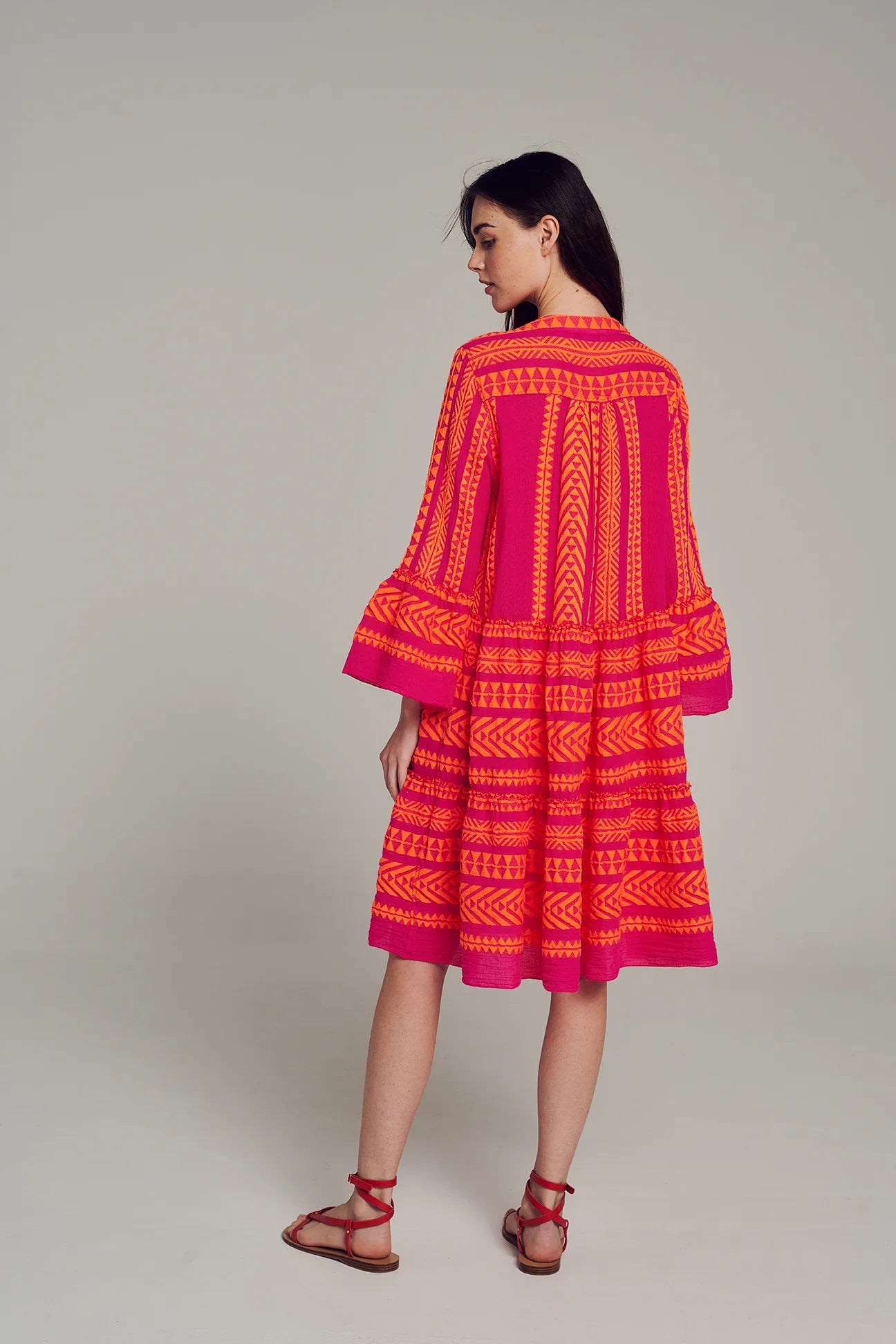 Pink notch neck midi dress with long fluted sleeves and tripe tiered A line skirt with neon orange embroidery throughout