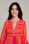 Pink notch neck midi dress with long fluted sleeves and tripe tiered A line skirt with neon orange embroidery throughout