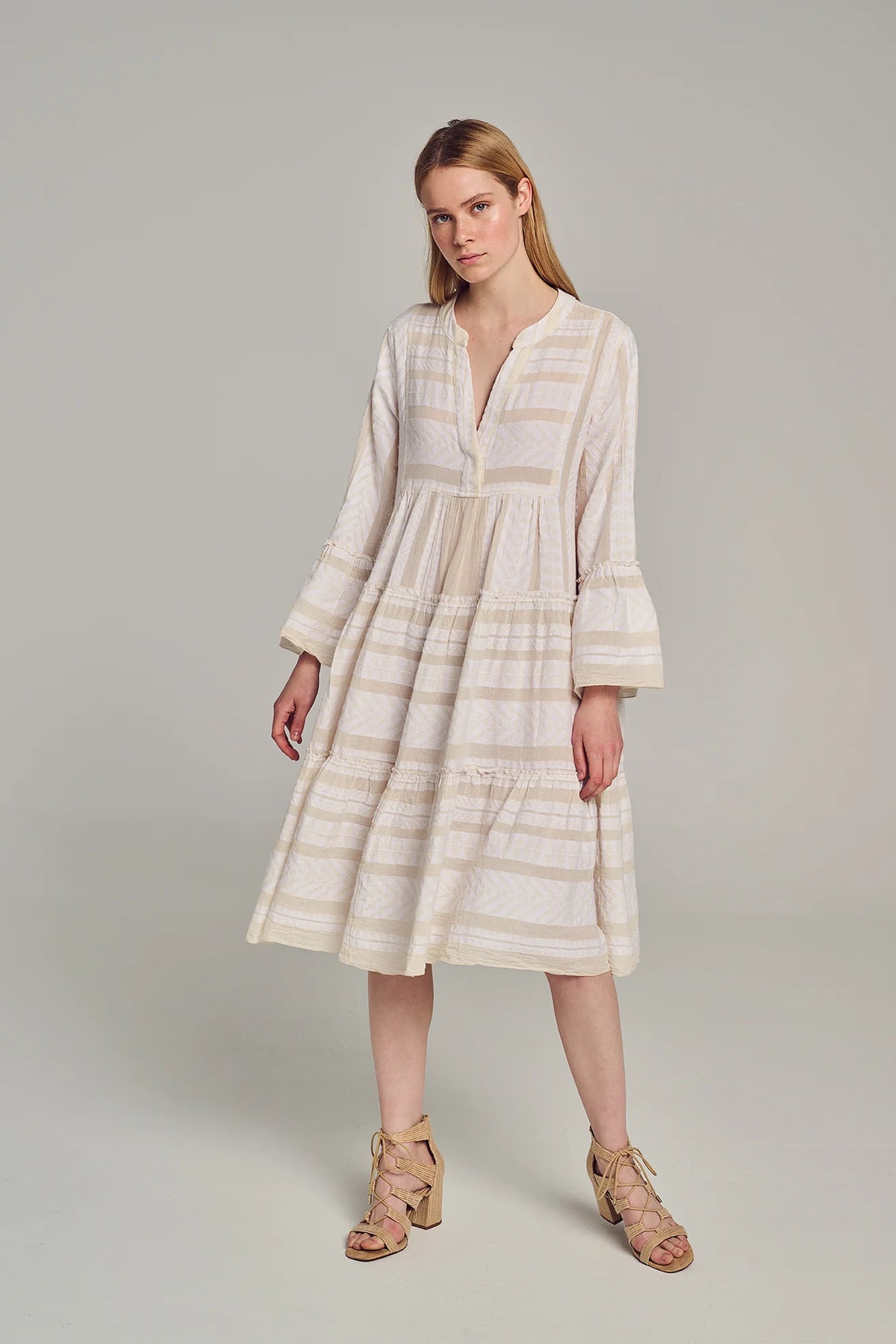 Ecru notch neck midi dress with long fluted sleeves and tripe tiered A line skirt with off-white embroidery throughout