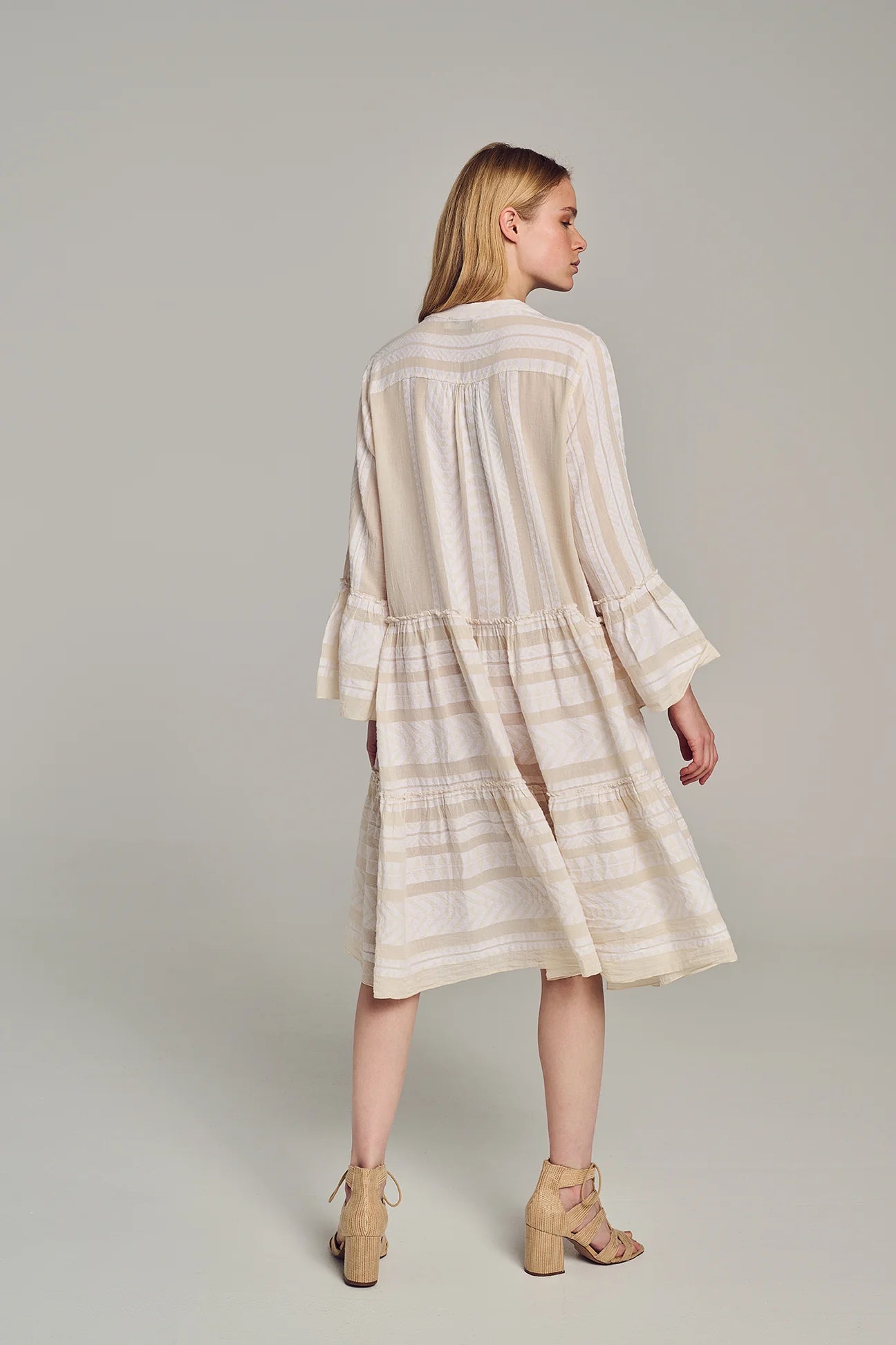 Ecru notch neck midi dress with long fluted sleeves and tripe tiered A line skirt with off-white embroidery throughout