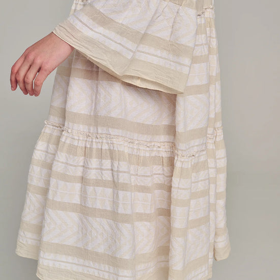 Ecru notch neck midi dress with long fluted sleeves and tripe tiered A line skirt with off-white embroidery throughout