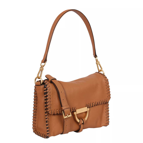 Side view of the tan leather bag with shoulder strap and top handle