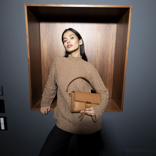 Model holding tan leather handbag