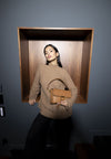 Model holding tan leather handbag