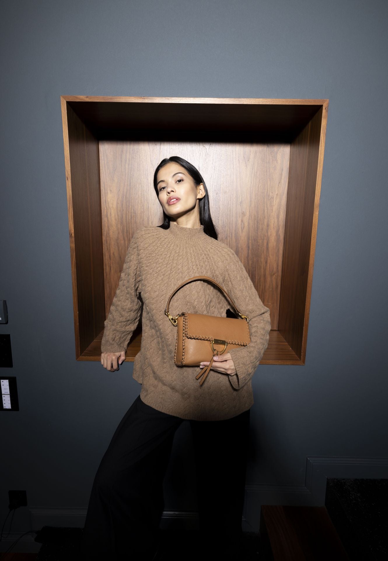 Model holding tan leather handbag
