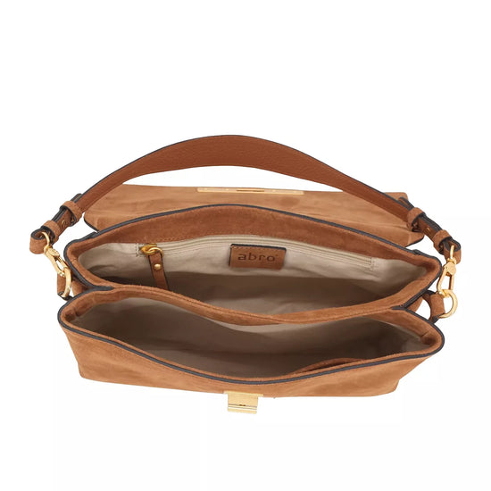 An open brown suede shoulder bag with gold-tone hardware, showing its interior compartments and a tan leather brand patch that reads 'abco'.