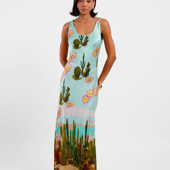 Woman wearing a sleeveless dress with cactus and floral design on a white background