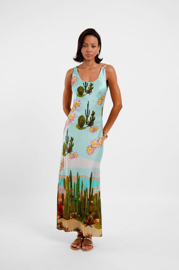 Woman wearing a sleeveless dress with cactus and floral design on a white background