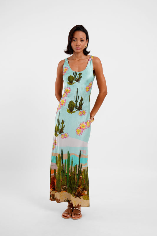 Woman wearing a sleeveless dress with cactus and floral design on a white background