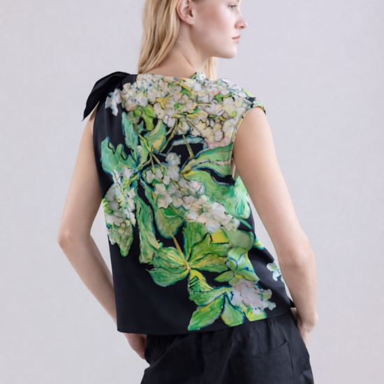 Woman wearing a silk sleeveless top with floral design on a plain background