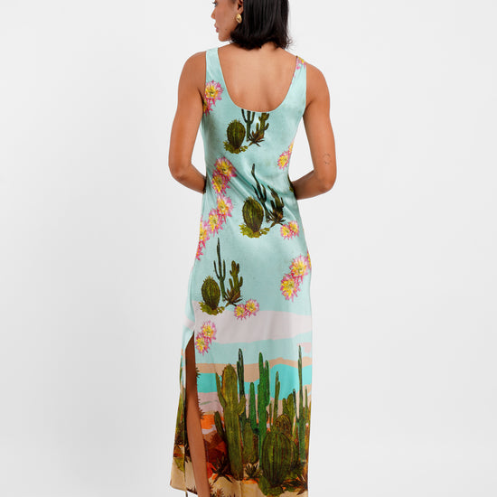 Woman wearing a dress with cactus and floral design on a white background