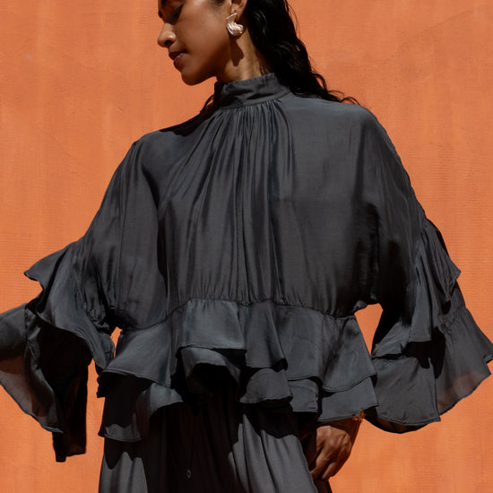 Woman wearing a black ruffled blouse against an orange background