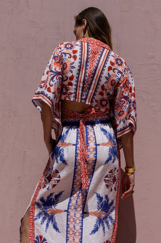 Woman wearing a colorful patterned outfit against a pink wall