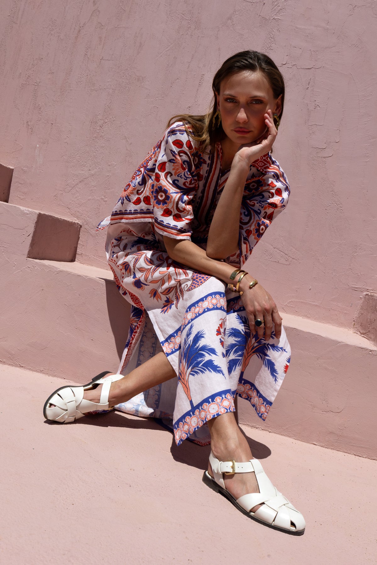 Woman in a colorful dress sitting on pink steps