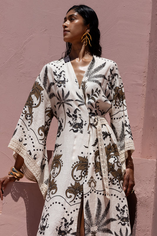 Woman wearing a white patterned dress against a pink wall