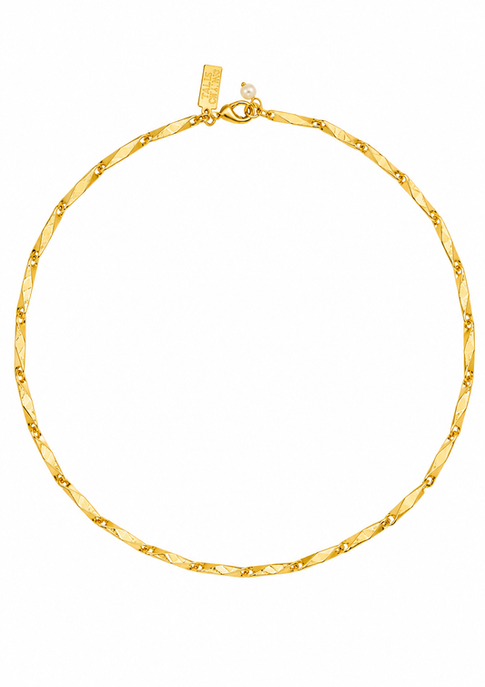 A close-up of a gold chain necklace with a textured, diamond-patterned center and small raised gold dots along the edges, shown against a plain white background.