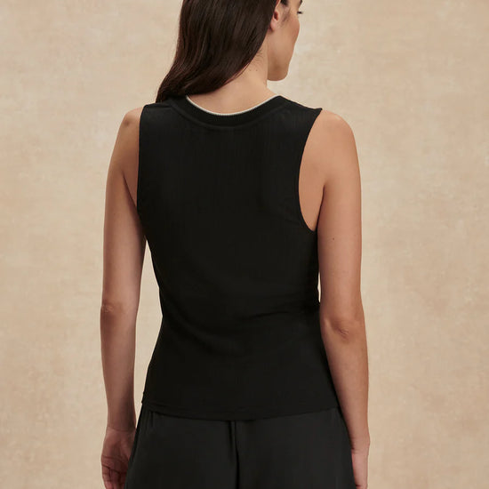 Woman wearing a black sleeveless top and shorts on a beige background