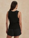 Woman wearing a black sleeveless top and shorts on a beige background