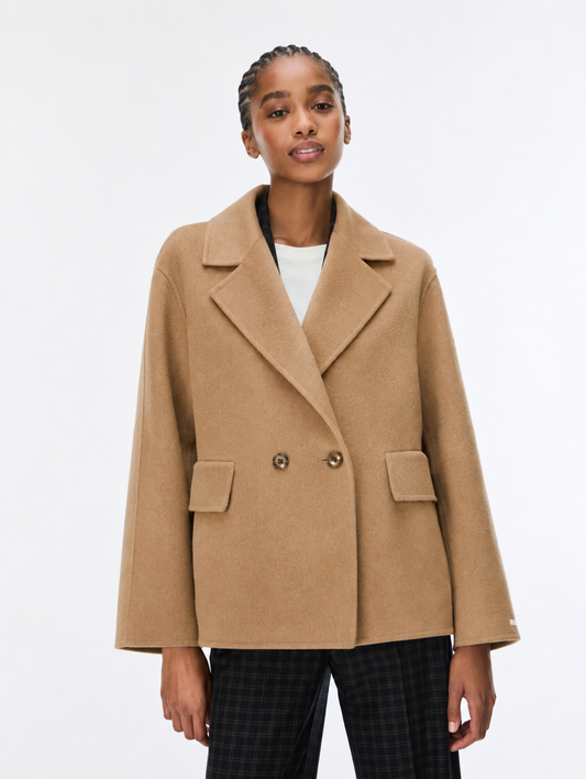 model wearing a single breasted camel coat on a white background 