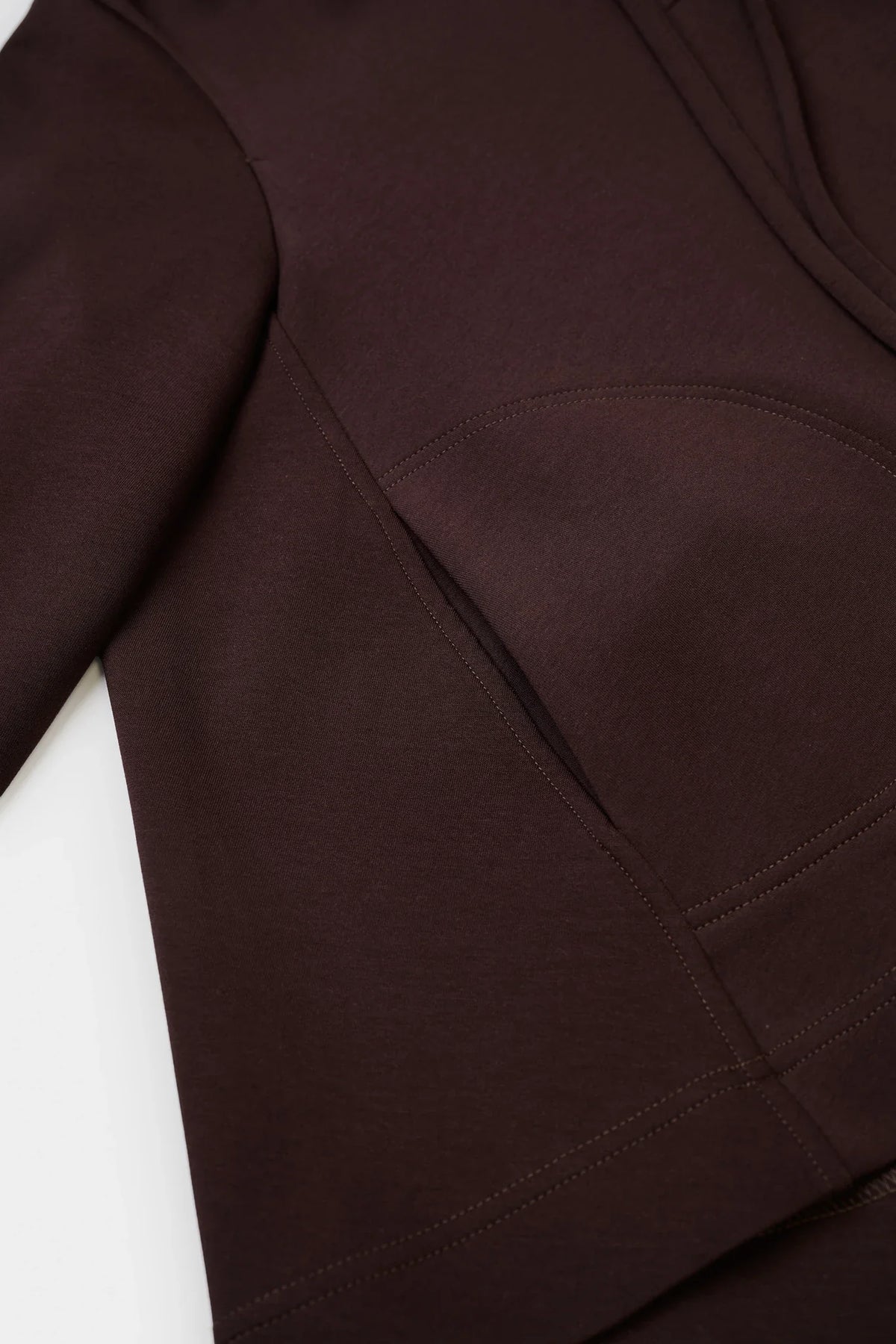 Close-up of a dark brown garment, showing the fabric texture and a curved seam detail.
