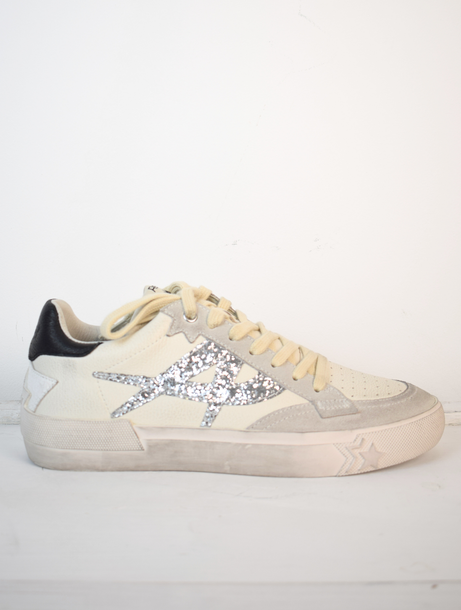 Off white trainers with silver A on the side and black patch on back of heel 