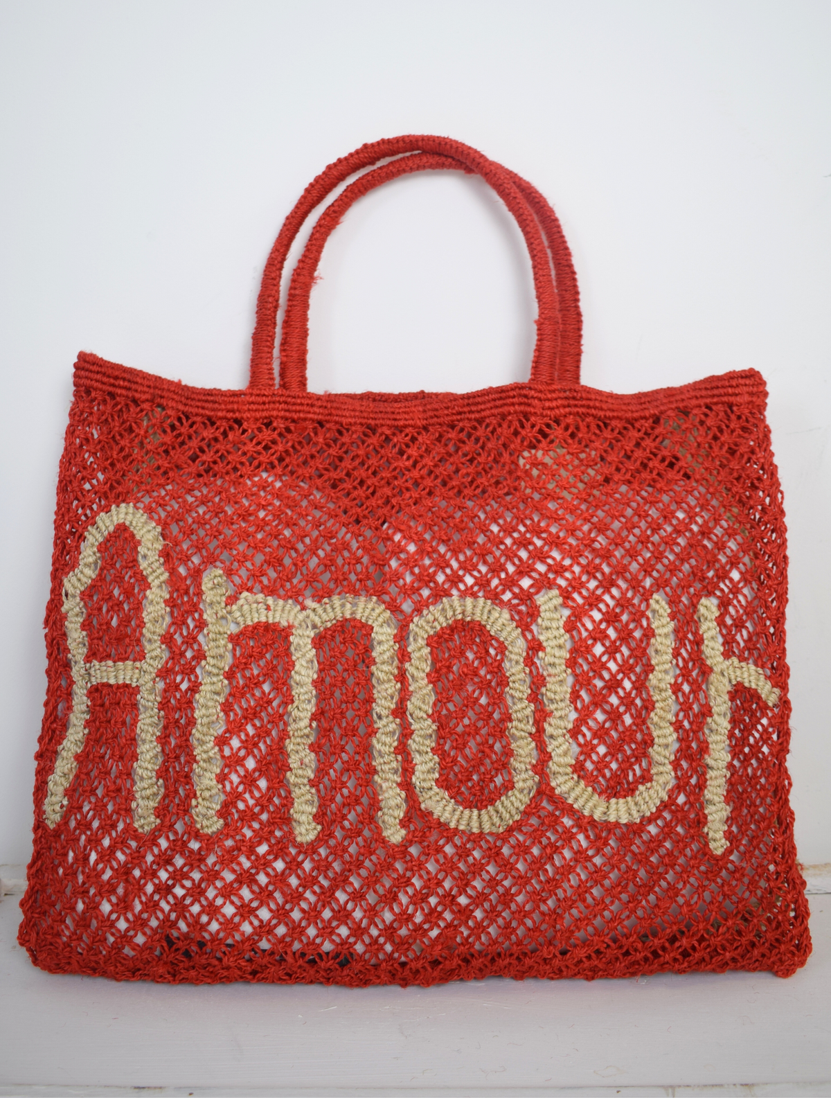 red woven bag with nude writing on saying Amour