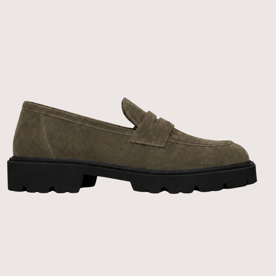 A single khaki suede penny loafer with a chunky black sole, shown in a side profile against a light gray background.