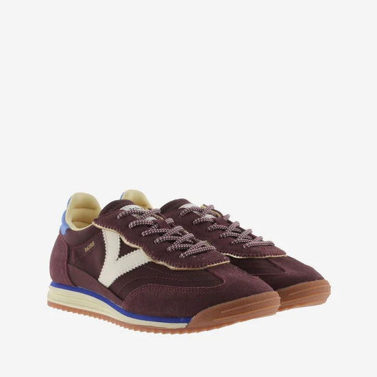 burgundy baseball style trainers with blue back, white v and a serrated tread front view 
