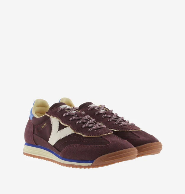 burgundy baseball style trainers with blue back, white v and a serrated tread front view 