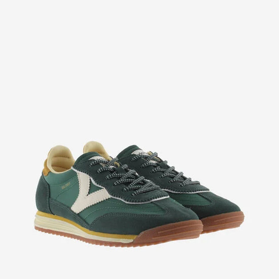 green baseball style trainers with yellow back, white v and a serrated tread front view 