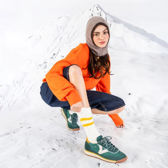 green baseball style trainers with yellow back, white v and a serrated tread model shot