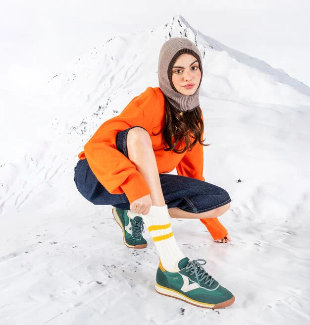 green baseball style trainers with yellow back, white v and a serrated tread model shot