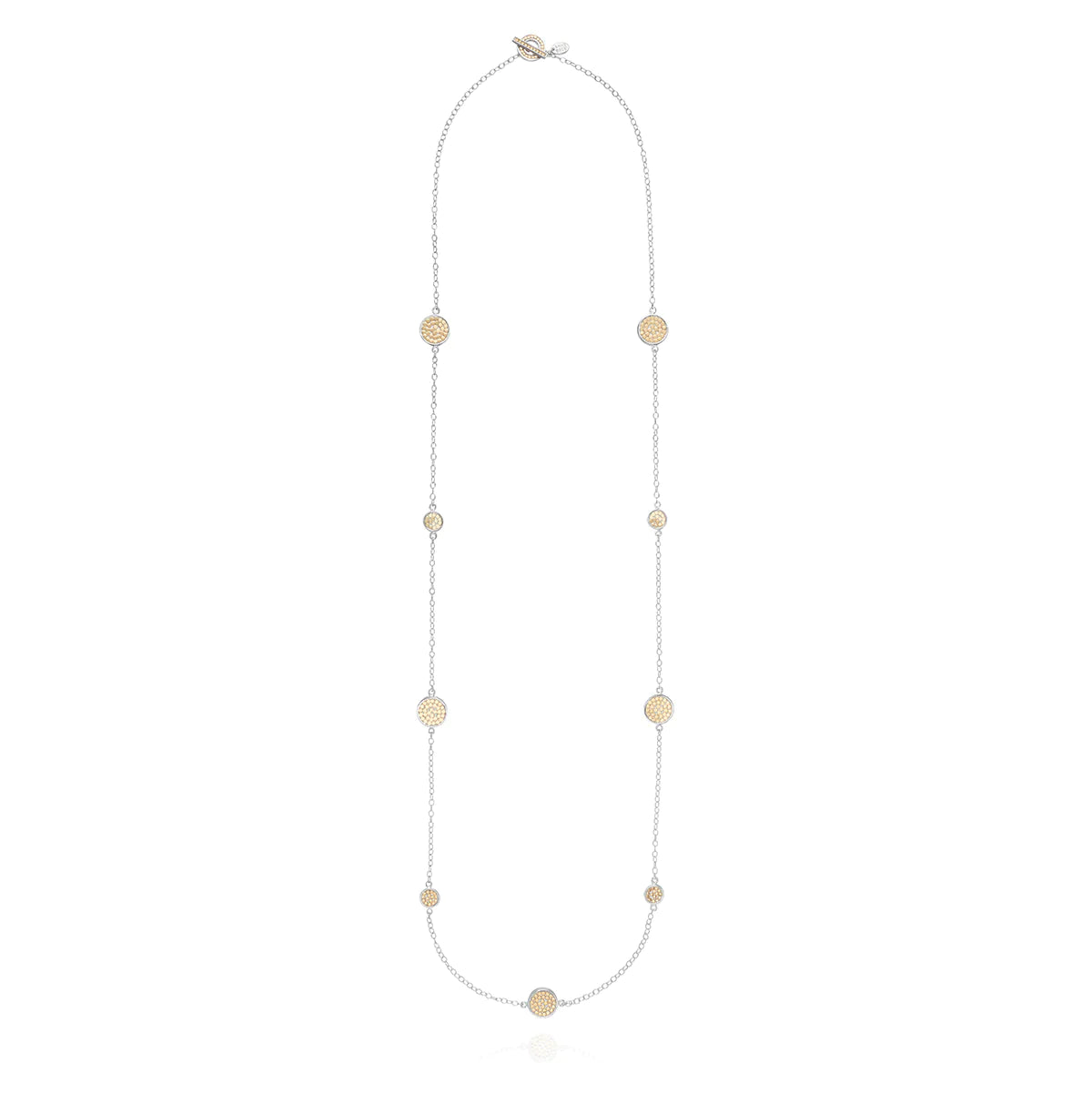 Long silver station necklace with alternating small and medium silver discs with gold dot details